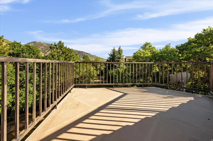 Expansive outdoor decking with metal railings, surrounded by mature trees and distant mountains