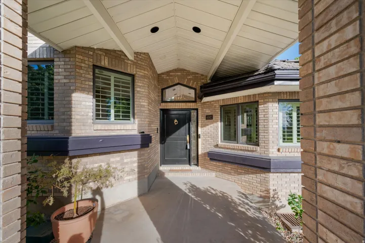 Brick exterior with a covered entry, dark-framed windows, and an arched transom window