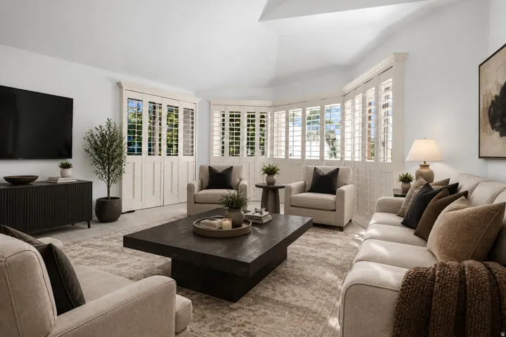 Vaulted ceilings, bay window with plantation shutters, white walls, and recessed lighting
