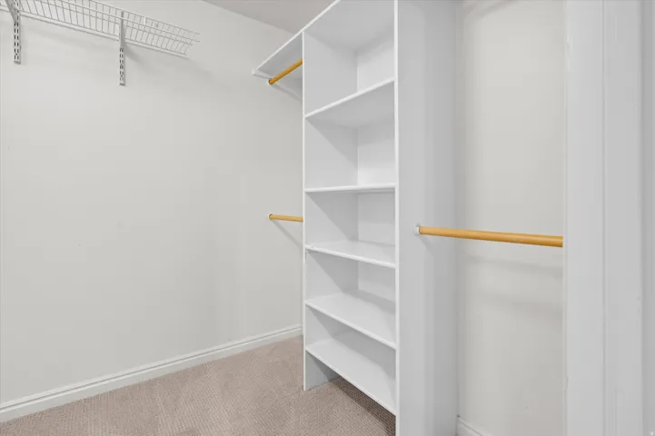 Built-in shelving unit, multiple hanging rods, wire shelving, and carpeting