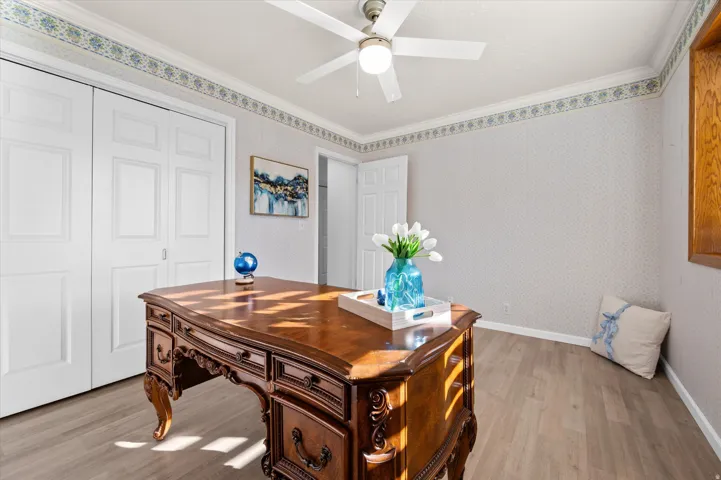 Wood-finish flooring, white bi-fold closet doors, ceiling fan with integrated lighting, and a white interior door