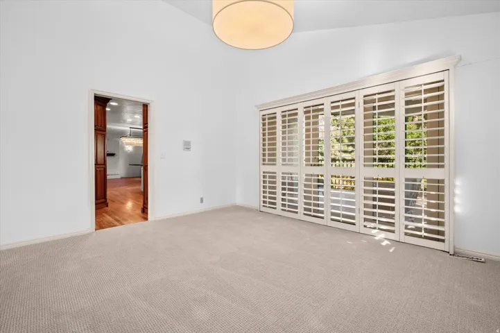 Vaulted ceilings, neutral carpeting, and white plantation shutters