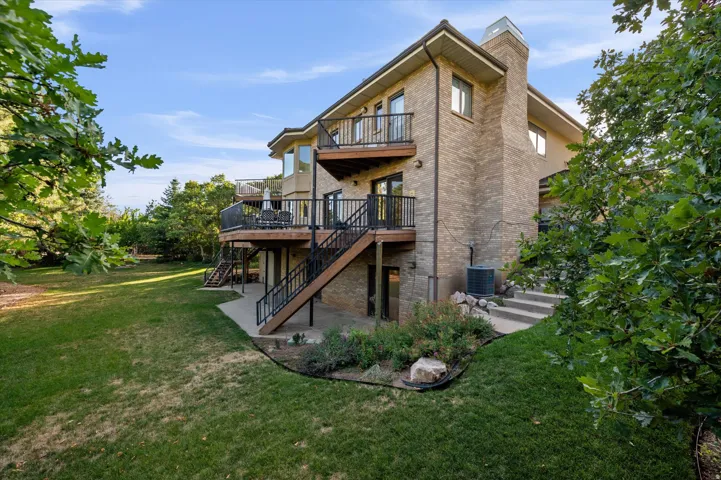 Brick exterior featuring multiple balconies, exterior staircase access, and a manicured lawn