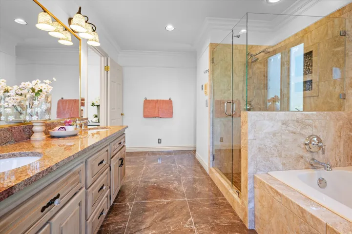 Dual vanity with granite countertop, glass-enclosed shower, built-in soaking tub, and tile flooring
