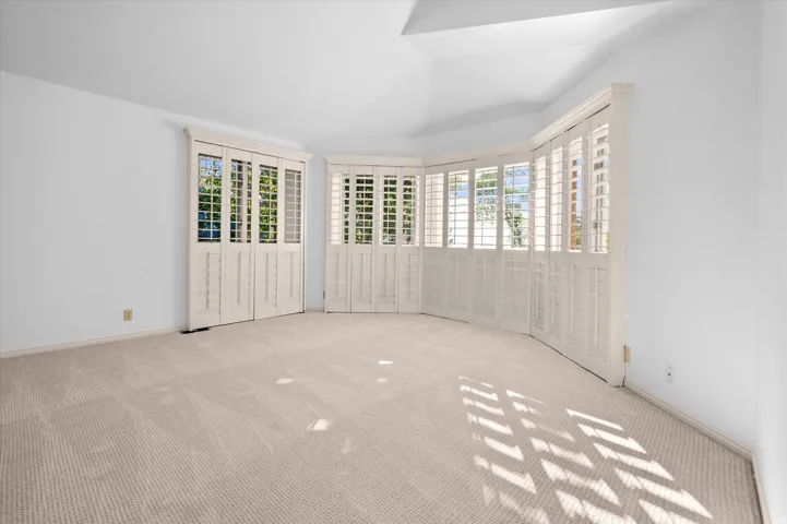 Plush carpeting, white walls, and a multi-paned window system with plantation shutters