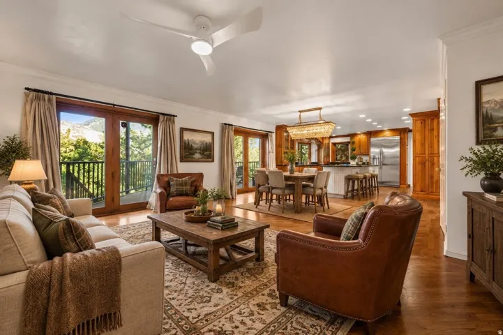 Spacious interior featuring wood-finish flooring, a contemporary ceiling fan, and multiple sets of glass-paneled double doors opening to an outdoor balcony
