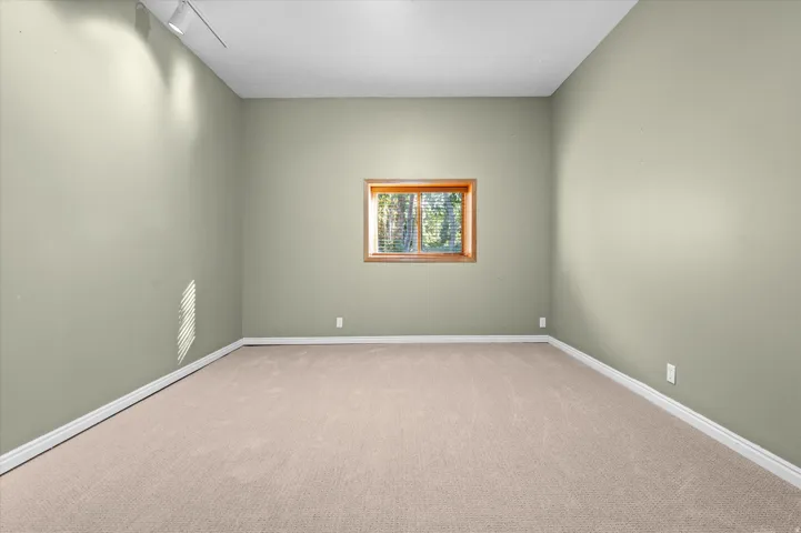 Recessed window with wood-finish trim, neutral-tone carpeting, and track lighting