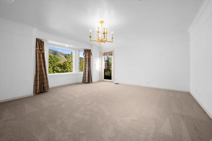 Expansive room featuring a bay window, wall-to-wall carpeting, and a gold-tone chandelier