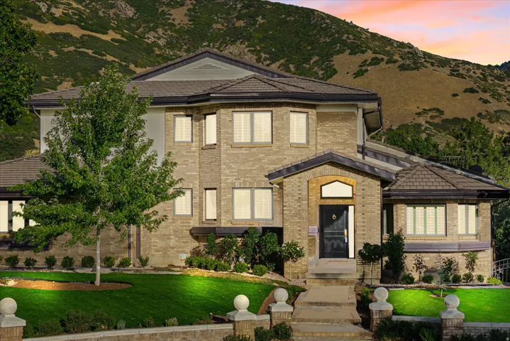 Brick exterior with multiple gables, a covered entry, established landscaping, and a terraced front yard