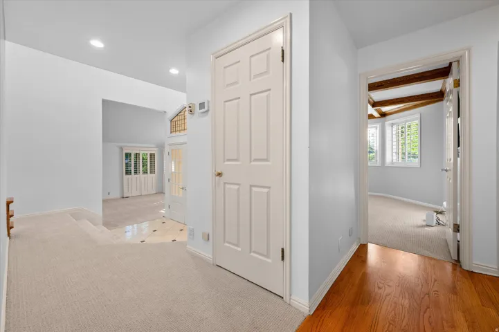 Recessed ceiling lights illuminate a carpeted hallway with a wood-finish handrail