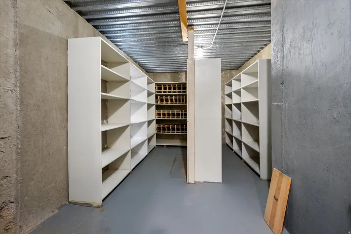 Extensive built-in shelving, additional built-in cubby storage, concrete walls, and painted concrete flooring