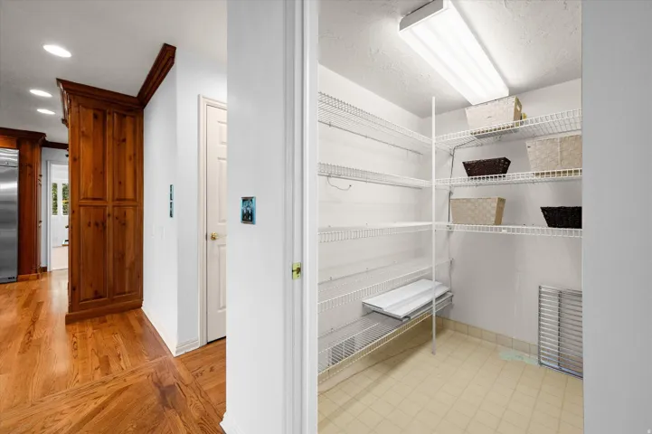 Wood-finish flooring, built-in cabinetry, recessed lighting, and a pantry with wire shelving