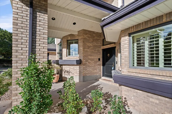Brick exterior with contrasting dark trim, covered entry, recessed lighting, and a dark paneled front door