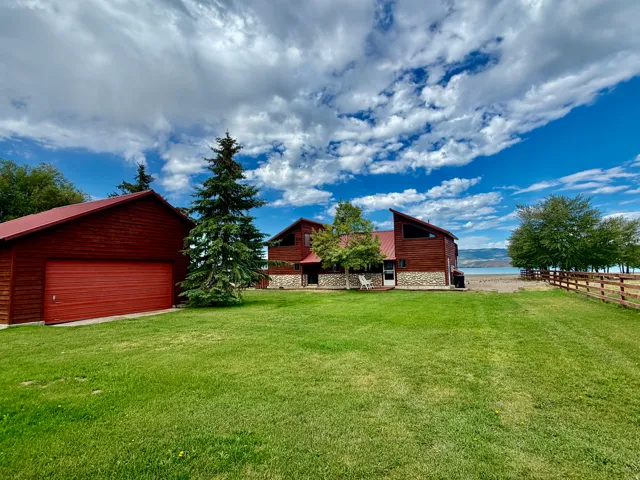 Wood-sided dwelling with a red metal roof and stone foundation