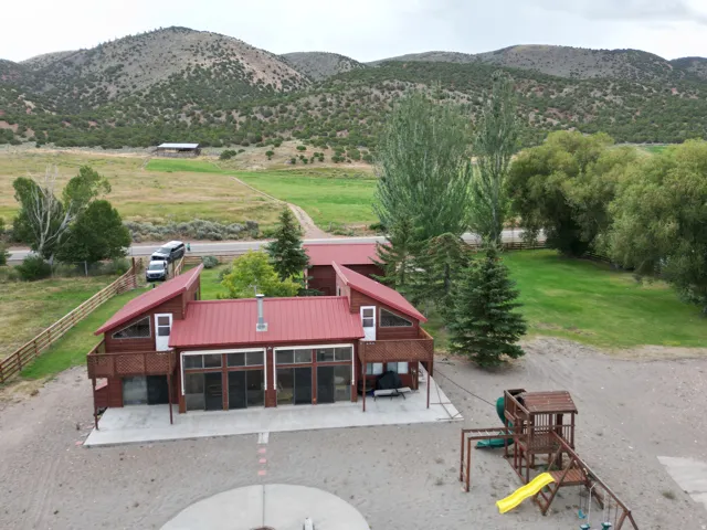 Red metal roof architecture with multiple large windows, elevated deck, and a concrete patio