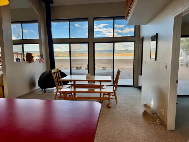 Floor-to-ceiling windows, a black cylindrical wood-burning stove, and light-colored flooring