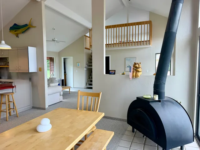 Vaulted ceilings, exposed beams, open loft area with wood railing, spiral staircase, and built-in wood-burning oven