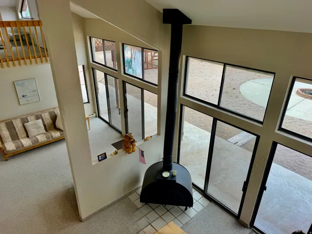 Soaring ceilings with a lofted area, multiple large windows, a freestanding fireplace, and tiled flooring