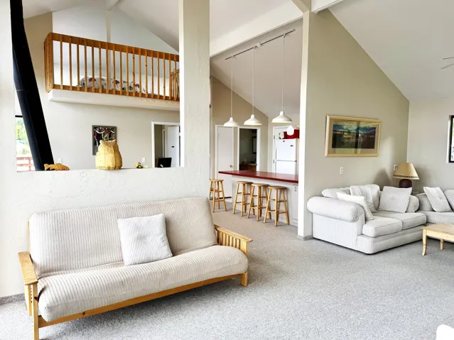 Vaulted ceilings, open concept design, a wood stove, and a loft area with wood railing