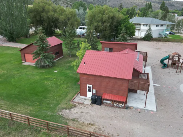 Brown siding structure with a red metal roof, elevated wooden deck, and a detached brown siding garage with a red metal roof