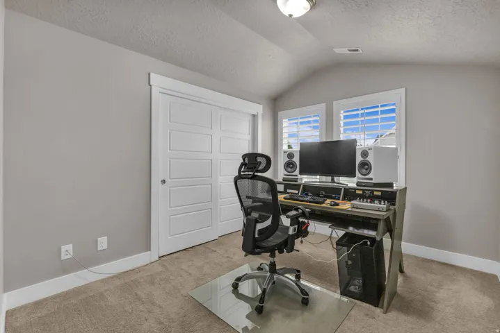Carpeted flooring, vaulted ceiling, dual windows with blinds, and white paneled sliding closet doors