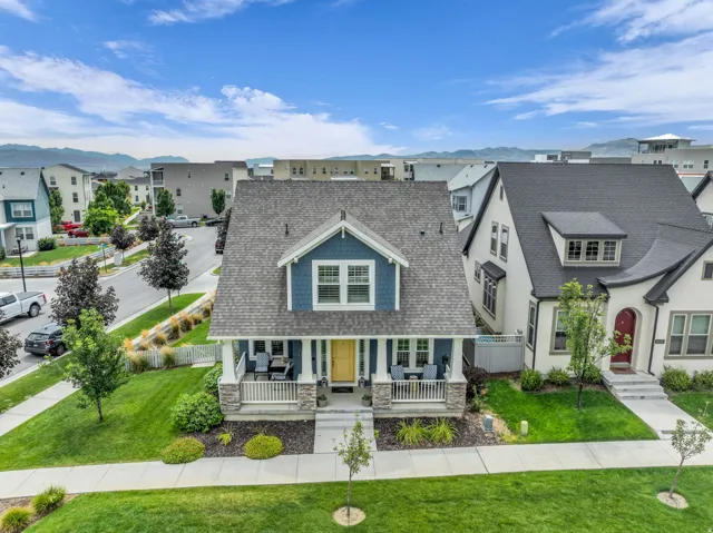 Gable roofline, prominent dormer, covered front porch, stone column bases, and a vibrant yellow entry door