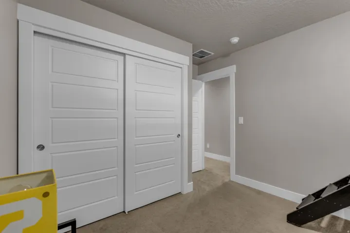 Sliding closet doors with clean lines, neutral wall color, white trim, and plush carpeting