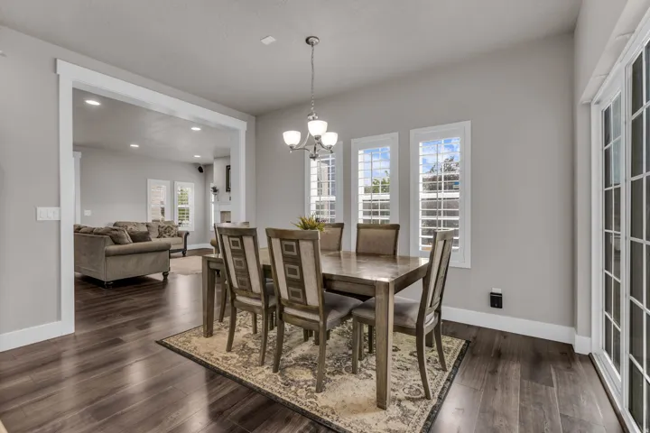 Spacious dining area with wood-finish flooring, a chandelier, and multiple windows