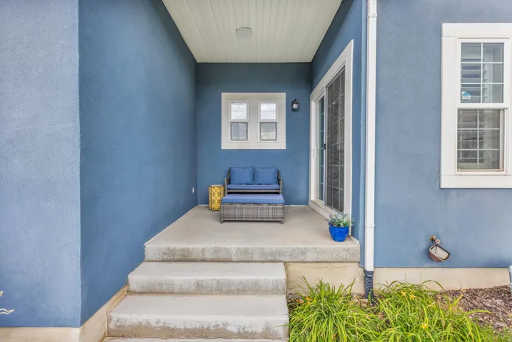 Covered patio with concrete steps, stucco exterior, and white framed windows