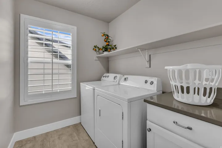 Laundry space featuring plantation shutters, neutral wall paint, wood-finish flooring, white cabinetry with hardware, and a solid surface countertop
