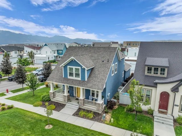 Blue siding exterior with dormer window, covered front porch, stone base columns, and a paved walkway