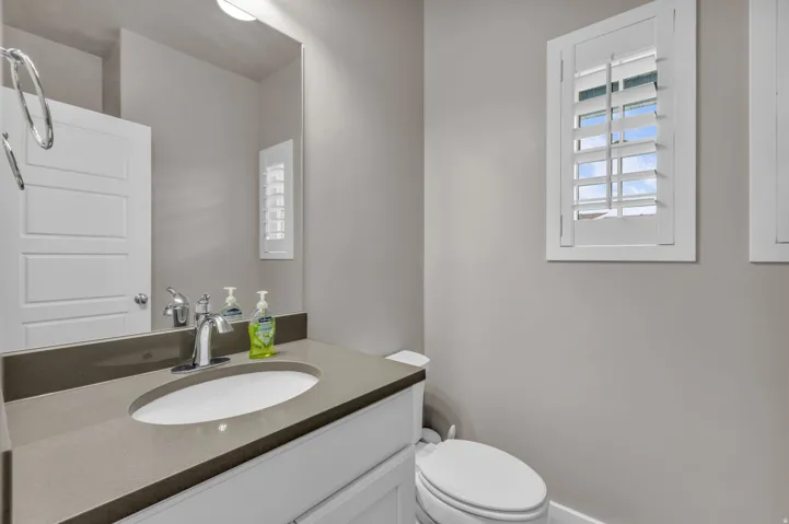 White vanity with an integrated sink, polished chrome faucet, and gray countertop