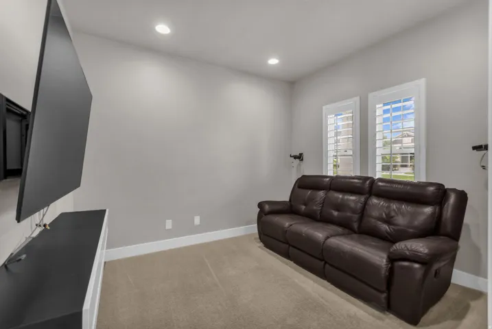 Recessed ceiling lighting, wall-mounted television, built-in entertainment console, and plantation shutters