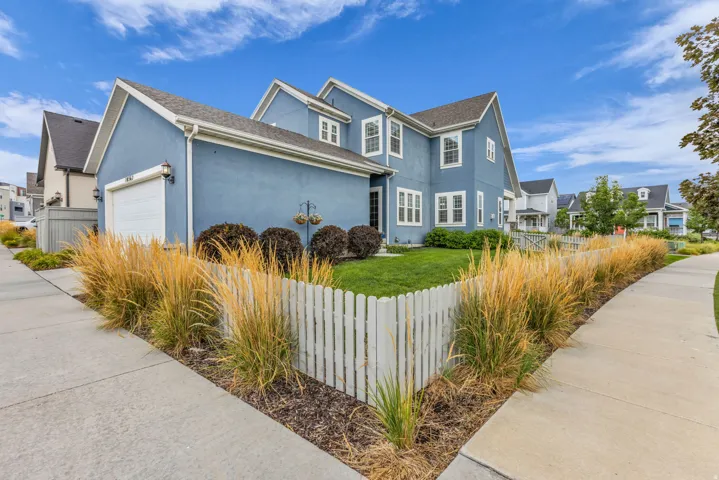 Two-story residence with a stucco exterior, white trim accents, and a front-facing garage