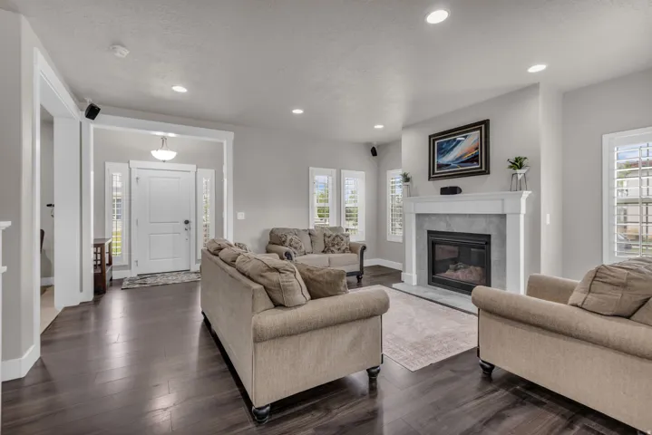 Spacious living area featuring wood-finish flooring, recessed lighting, and a fireplace with a light-toned surround