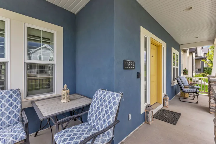 Covered porch featuring a blue stucco exterior, white window trim, and a bright yellow entry door