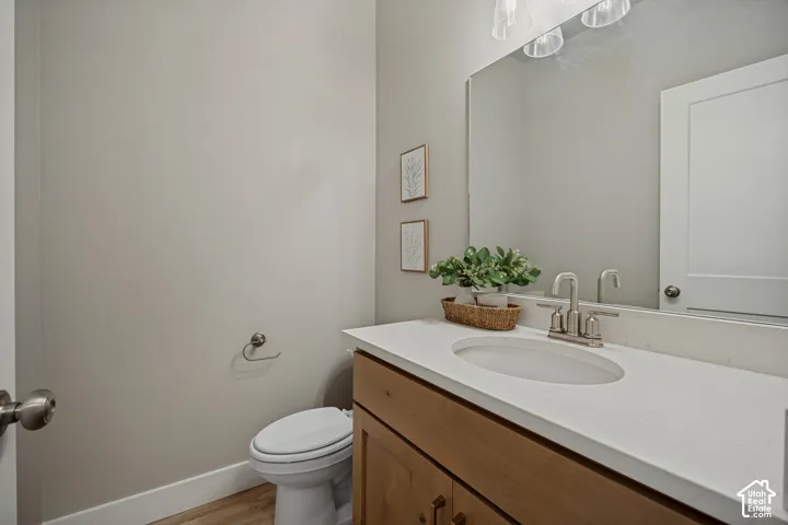 White countertop with an integrated sink, wood-finish vanity, and brushed nickel faucet