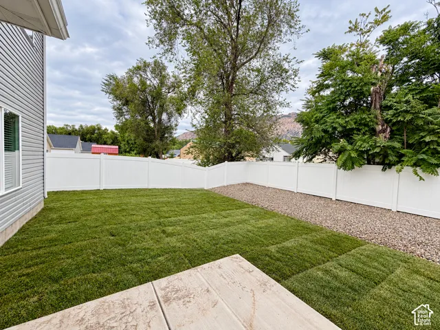 Expansive backyard featuring a newly laid lawn, full privacy fencing, and rock ditch