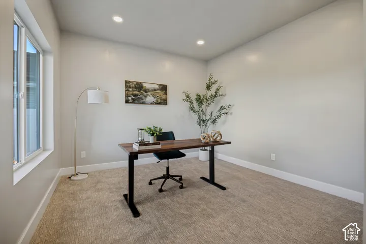 Recessed lighting, light-toned carpeting, ample natural light from a large window, and white trim