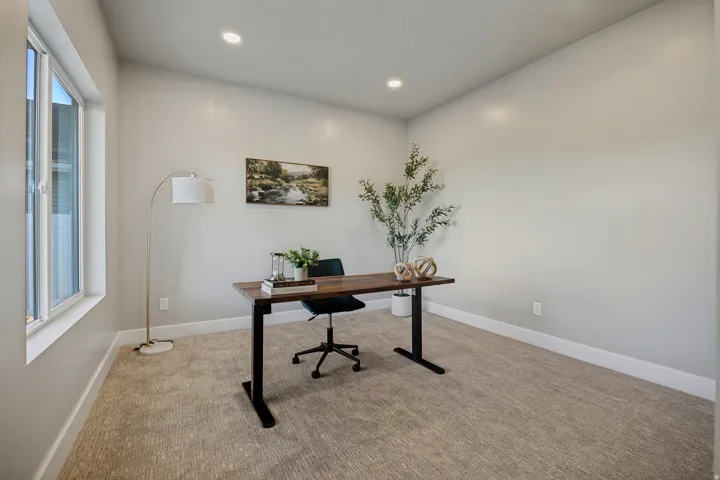 Recessed lighting, light-toned carpeting, ample natural light from a large window, and white trim