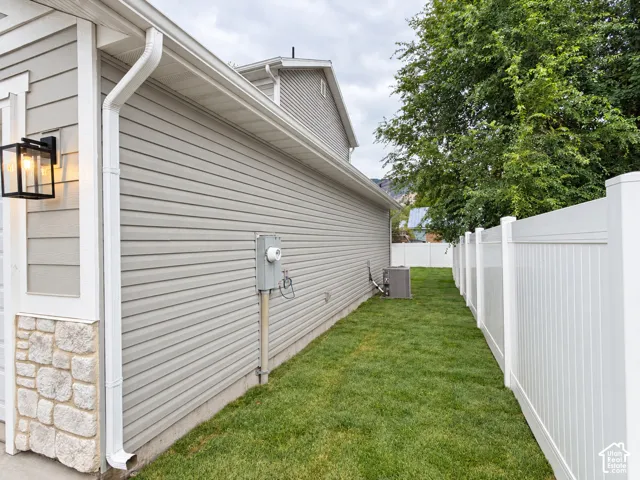 Siding exterior with stone accent, exterior lighting fixture, and a white privacy fence