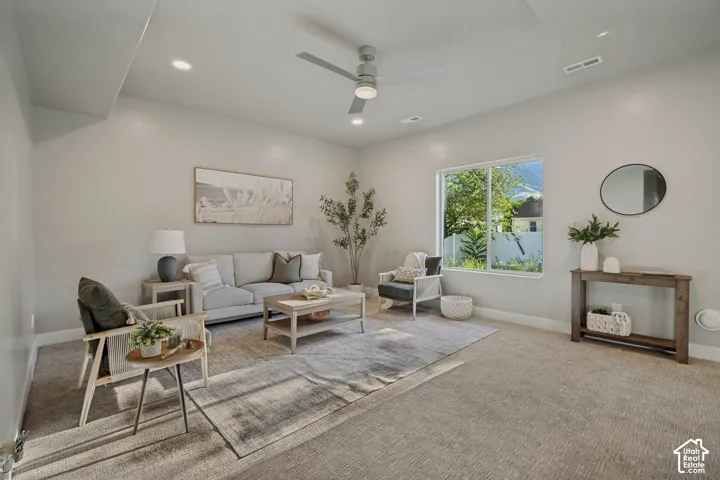Recessed lighting, ceiling fan, large window, light-toned carpeting, and neutral wall tones