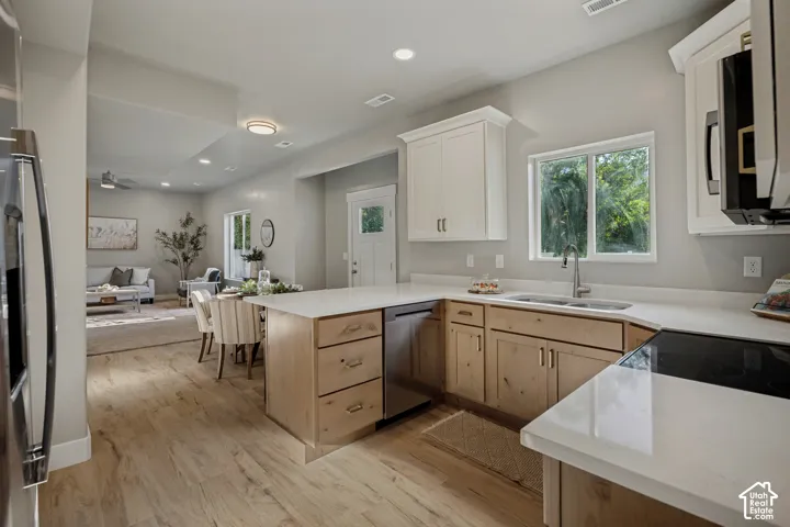 Modern kitchen featuring wood-finish flooring, light-toned cabinetry, white countertops, and stainless-steel appliances