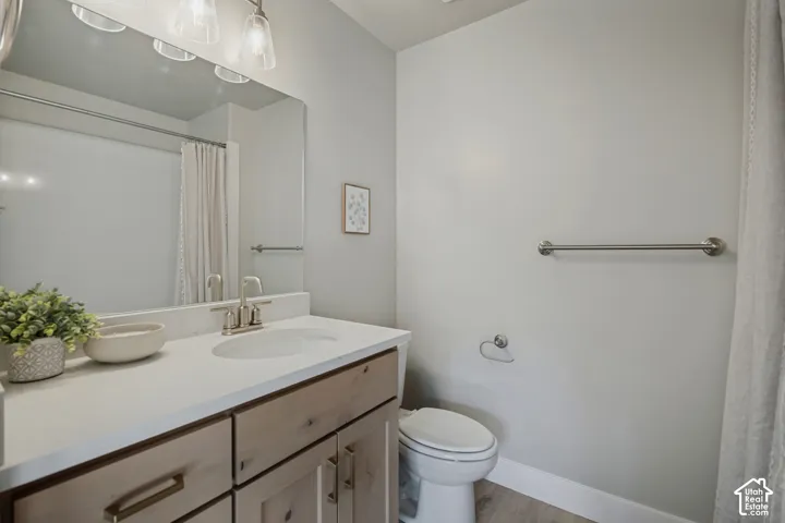 Vanity with light wood-finish cabinetry, white countertop, and single basin sink