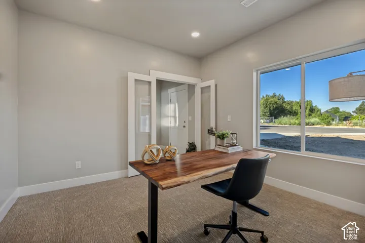 Recessed lighting, light gray wall paint, white trim, carpet flooring, and a large window