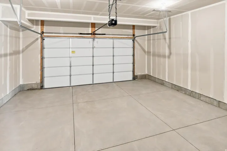 Spacious garage with a concrete floor, automatic garage door, and built-in overhead lighting