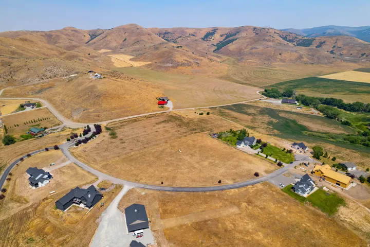Expansive rural landscape featuring scattered residential developments, curvilinear paved roads, and distant rolling hills