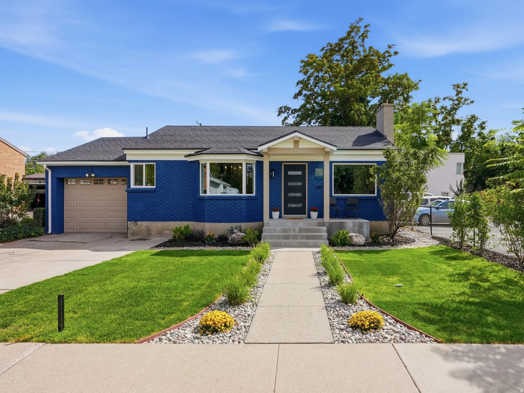 Blue exterior with white trim, a dark asphalt shingle roof, attached garage, and a concrete pathway leading to the front entry