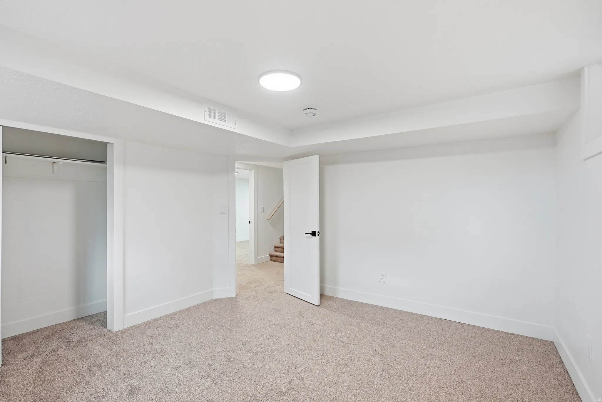 Plush carpeting, recessed lighting, white interior door with black hardware, and an open closet