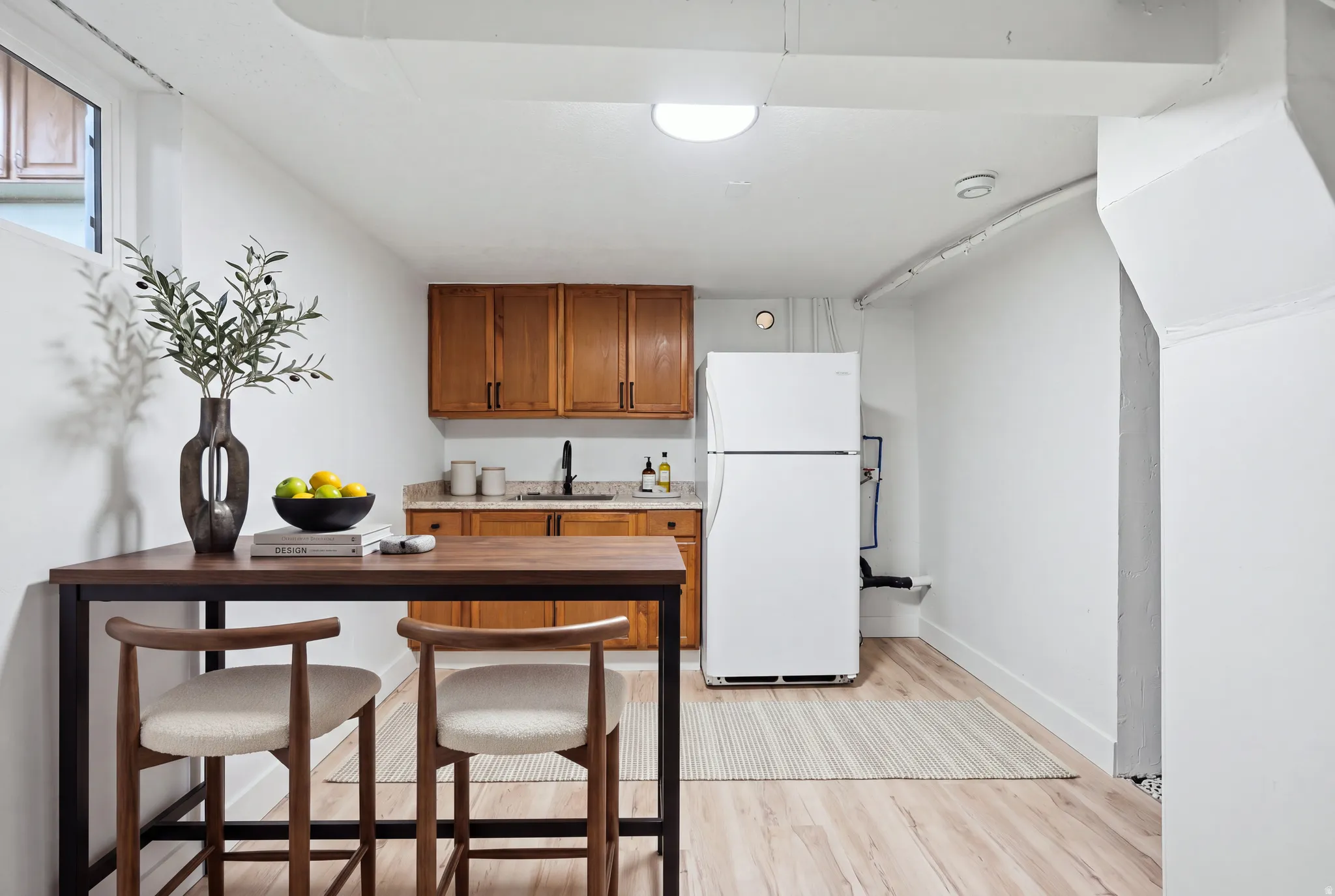 White appliances, wood-finish flooring, wood cabinetry, dark countertop, and a white ceiling